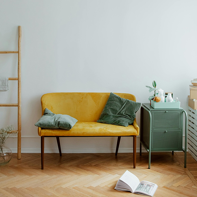 Divanetto giallo con cuscini e tavolino verde