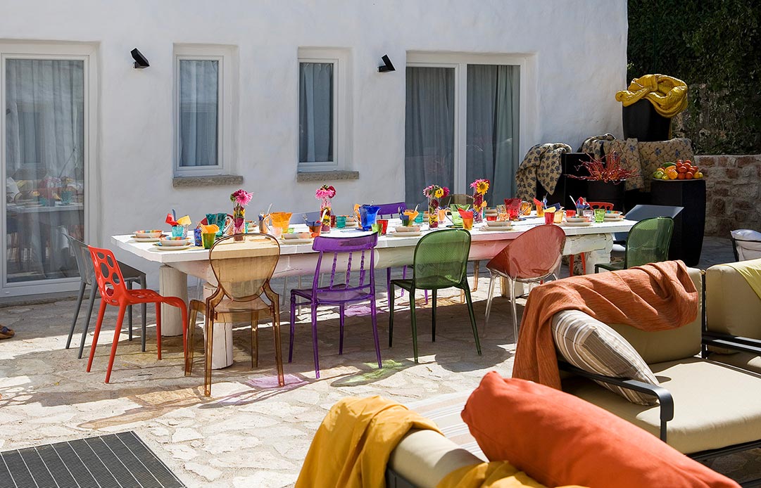 Tavola apparecchiata nel cortile di Villa Enego con sedie colorate
