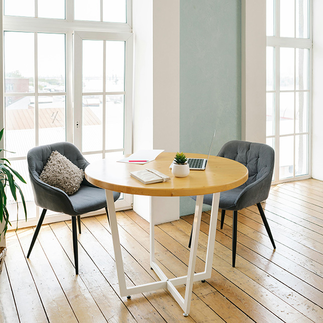 Tavolo rotondo con laptop e sedie davanti a grandi finestre