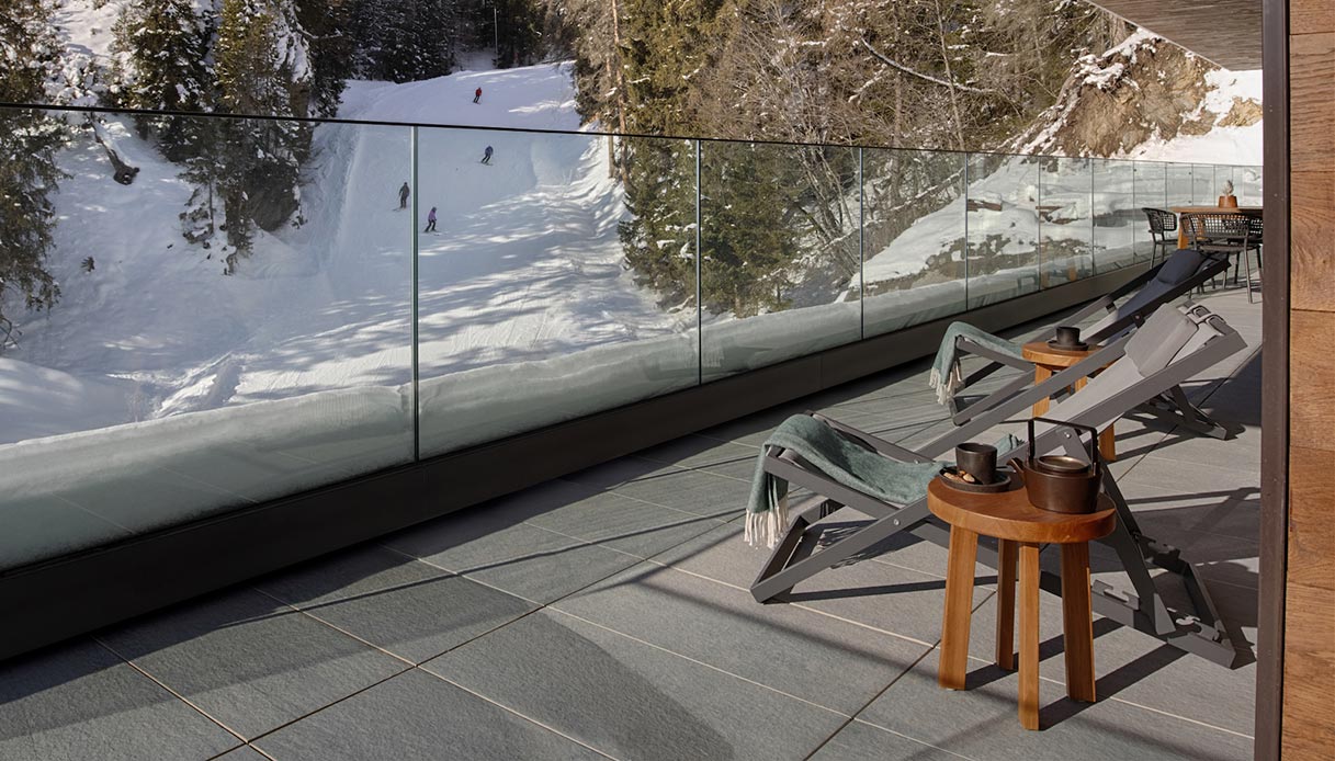 Terrazza in montagna con arredo da esterno invernale e vista sulle piste innevate