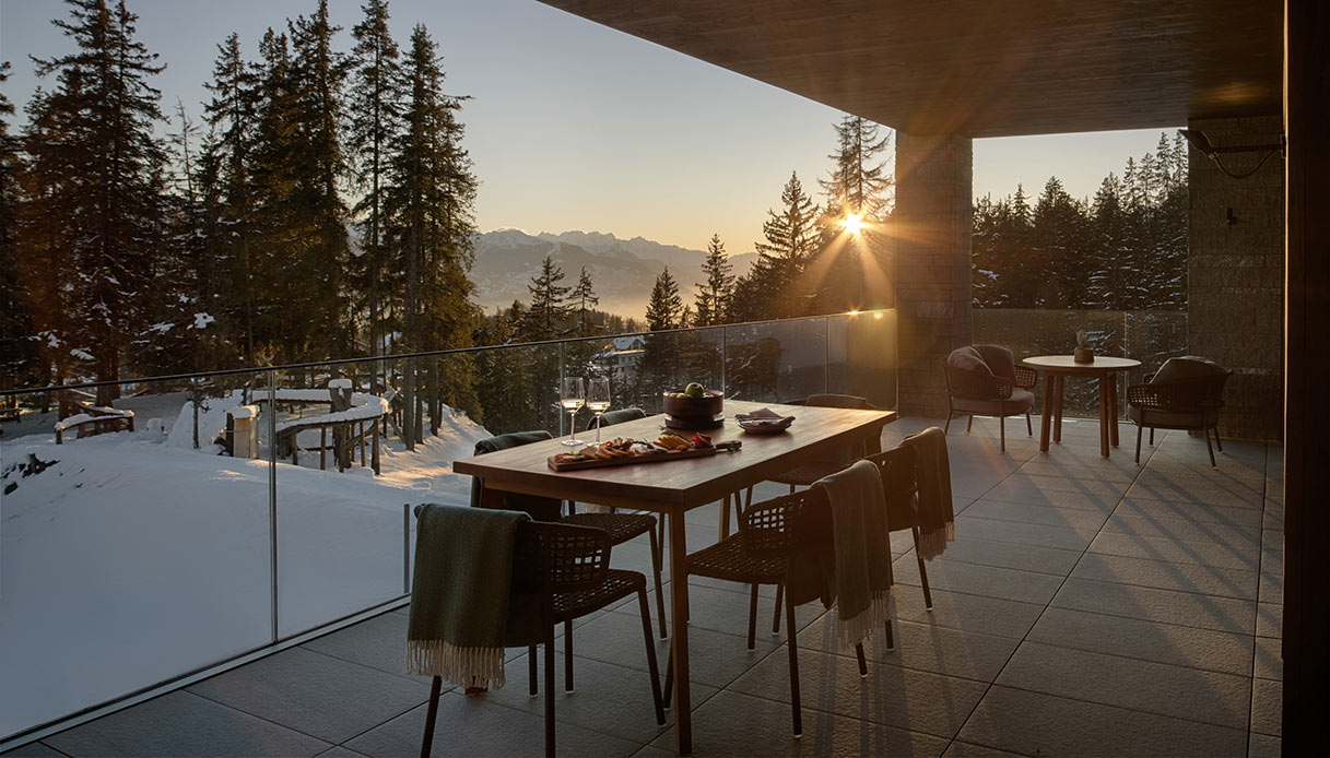 Zona pranzo outdoor in montagna con tavolo e sedute su terrazza panoramica innevata