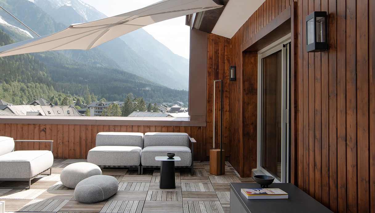 Balcone in legno con divani outdoor e vista sulle montagne