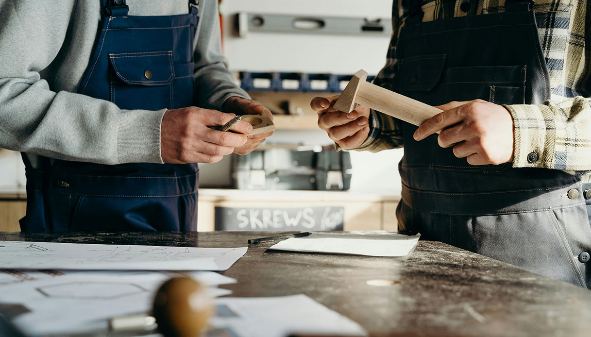 Artigiani al lavoro su elementi in legno per arredi di design etico e sostenibile