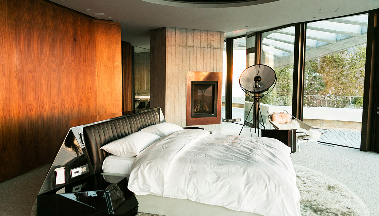 Camera da letto di design con camino moderno incassato nella parete e arredi minimal.