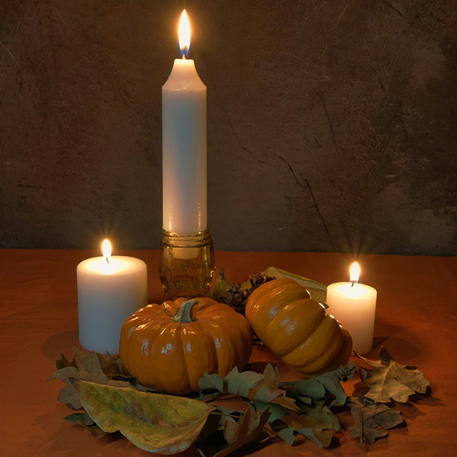 Centrotavola invernale con candele accese, zucche decorative e foglie secche