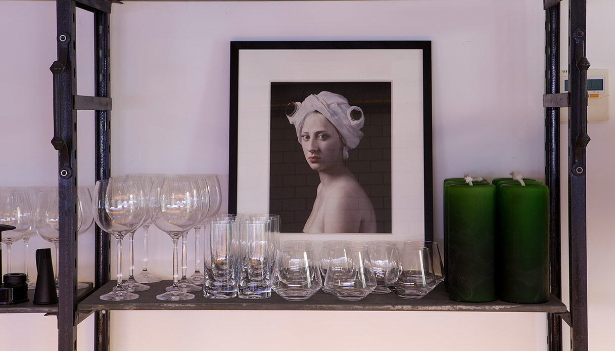 Scaffale in metallo con bicchieri di vetro e fotografia artistica incorniciata.