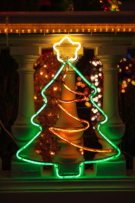 Albero di Natale stilizzato in neon verde e giallo posizionato su una balaustra esterna