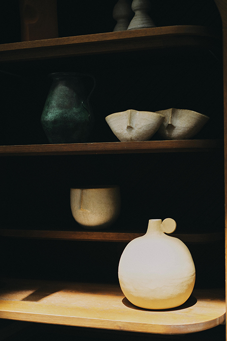 Ceramiche artigianali esposte su mensole in legno, dettagli materici del minimalismo caldo