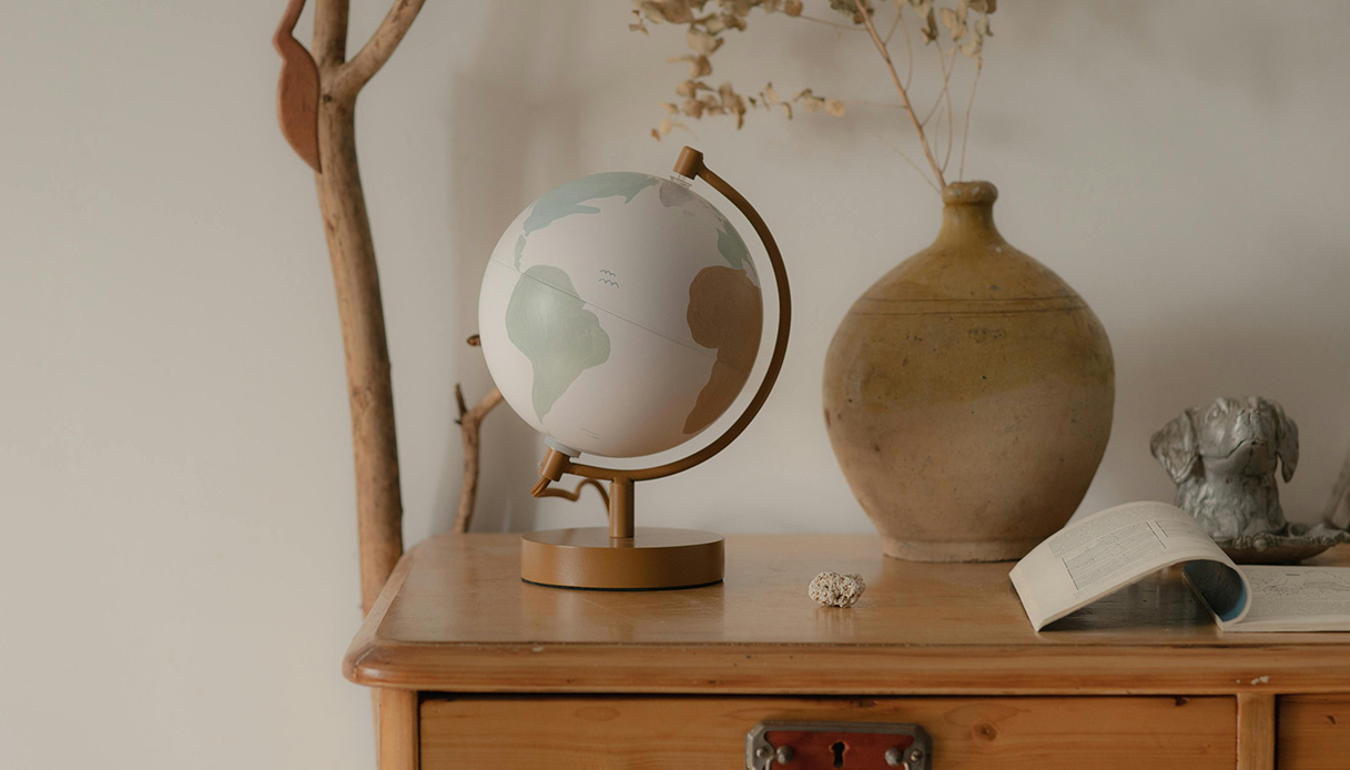 Mappamondo e oggetti decorativi su mobile in legno, in un interno dal mood minimalista caldo