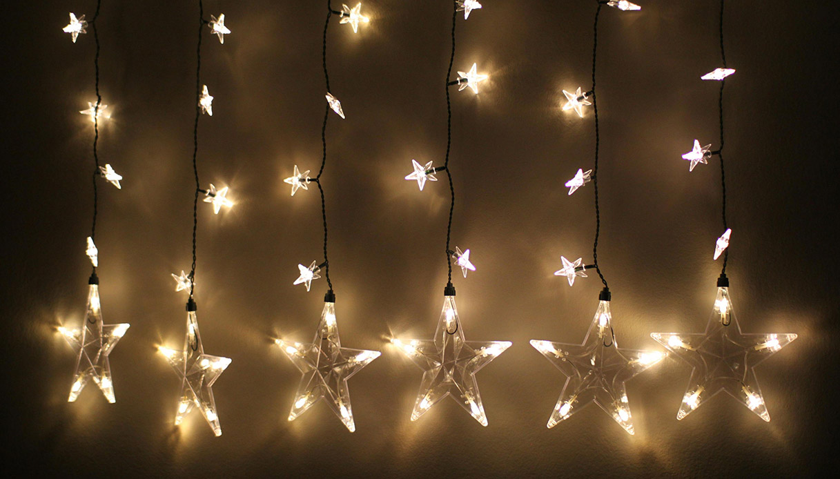 Tenda di luci natalizie a forma di stelle su parete.