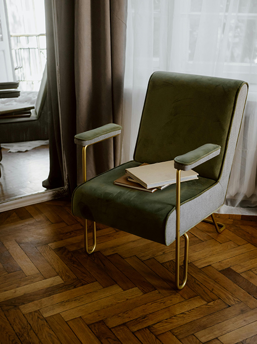 Poltrona vintage verde su parquet a spina di pesce in interno parigino