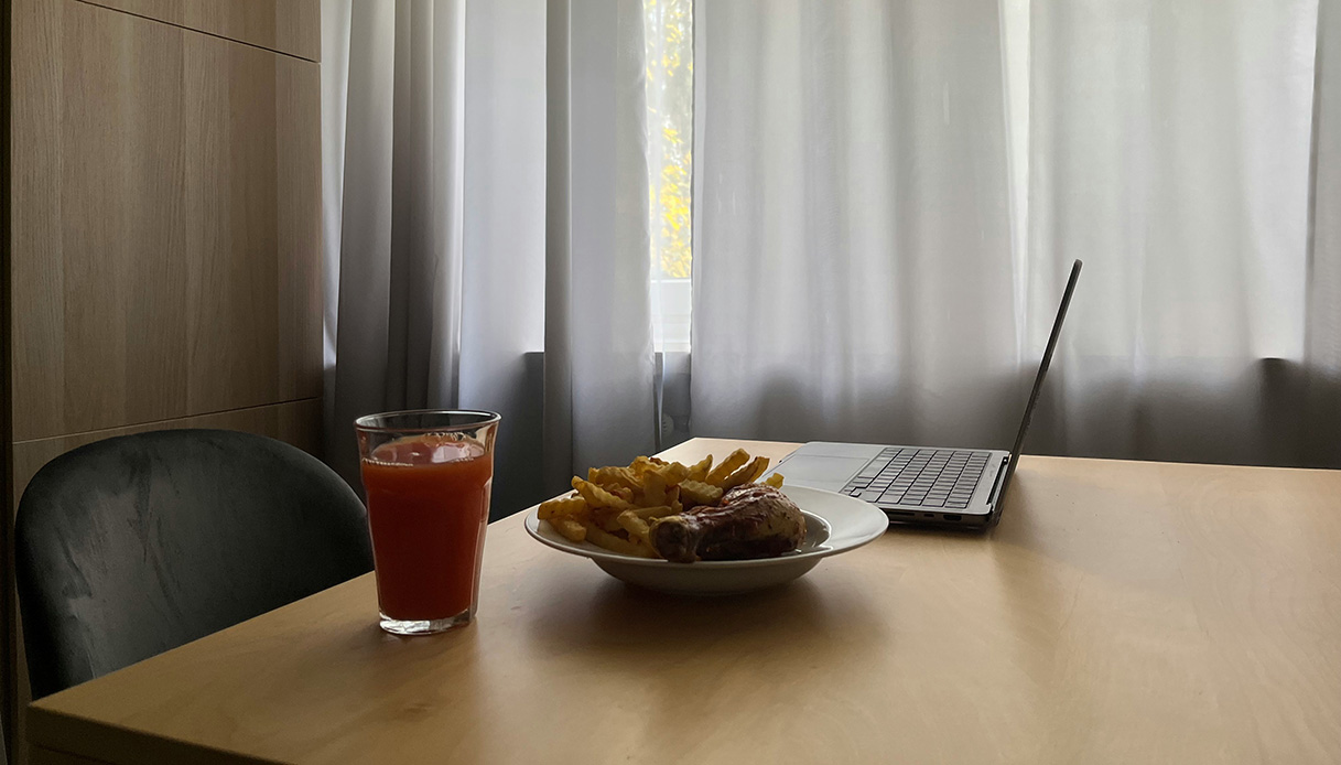 Tavolo da pranzo usato per mangiare e lavorare con laptop e piatto apparecchiato