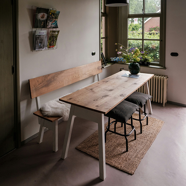 Sala da pranzo con tavolo in legno, panca e sgabelli in un ambiente luminoso
