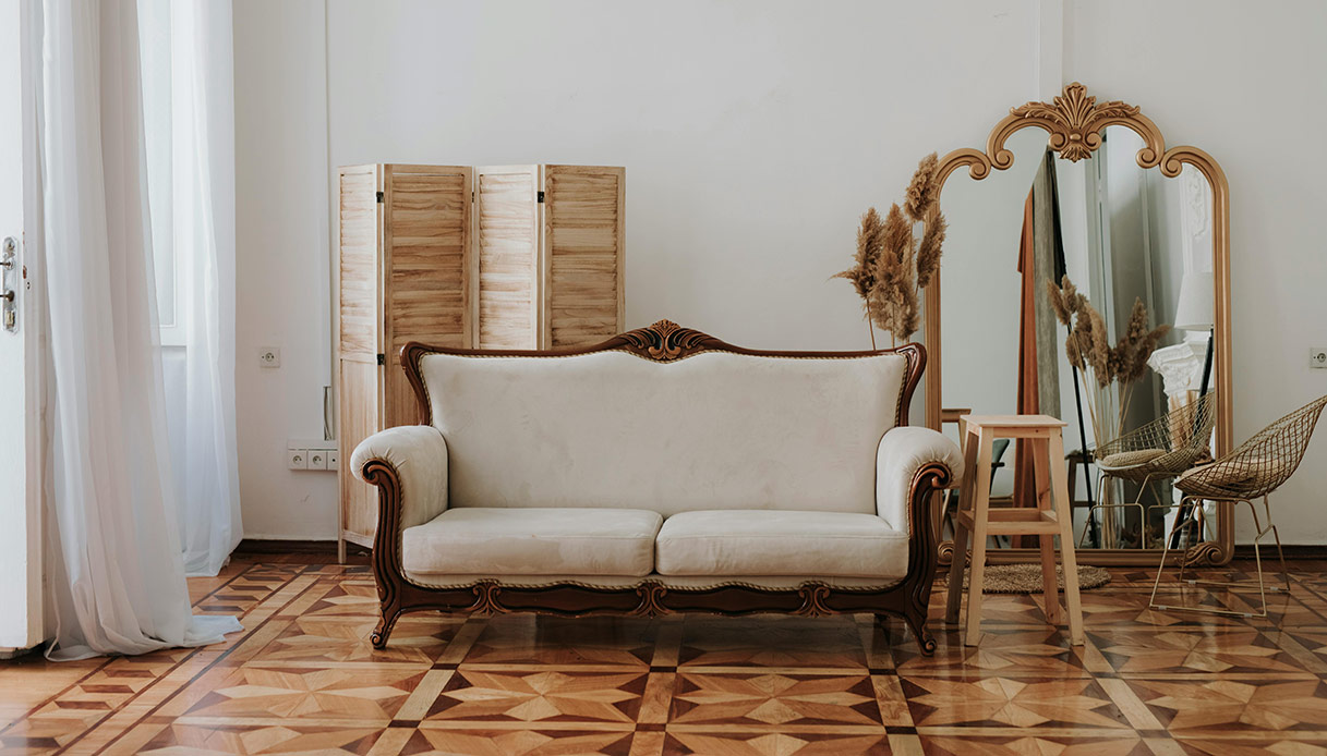 Salotto in stile parigino con divano classico, specchio dorato e parquet decorato