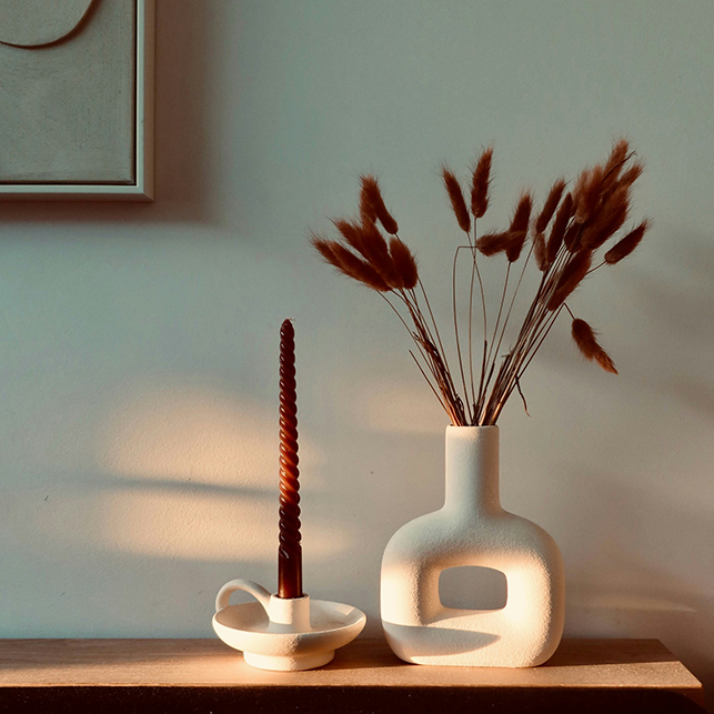 Vaso bianco con spighe secche e candela su mensola