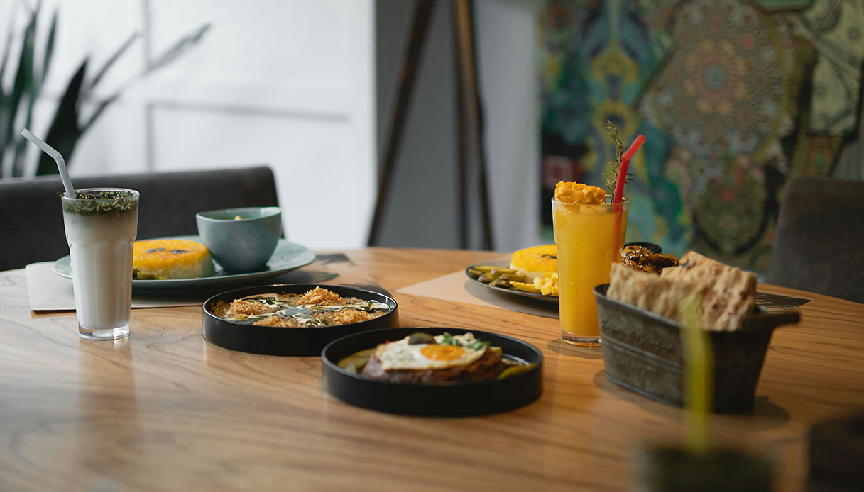 Tavolo apparecchiato con piatti, bevande e cibo per una colazione o cena informale