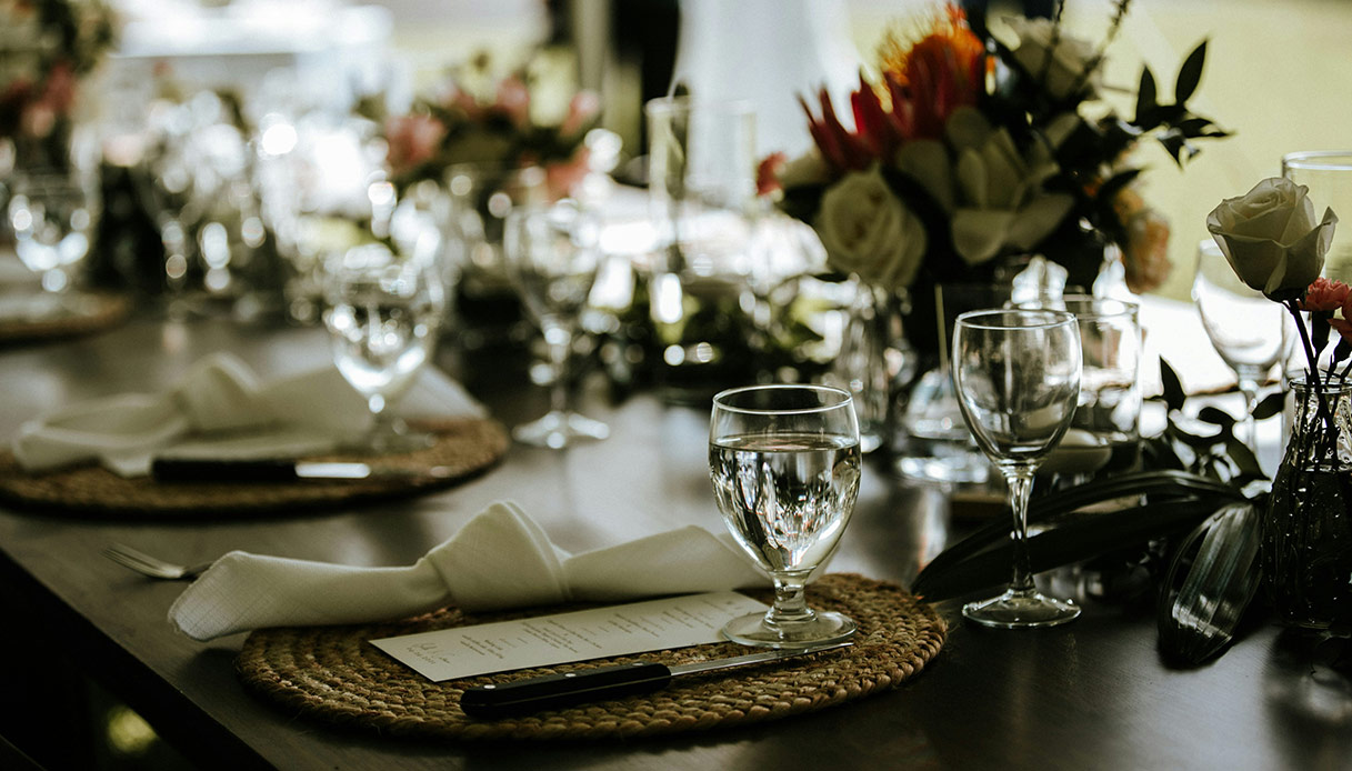 Tavola apparecchiata per pranzo domenicale con centrotavola floreale e mise en place curata