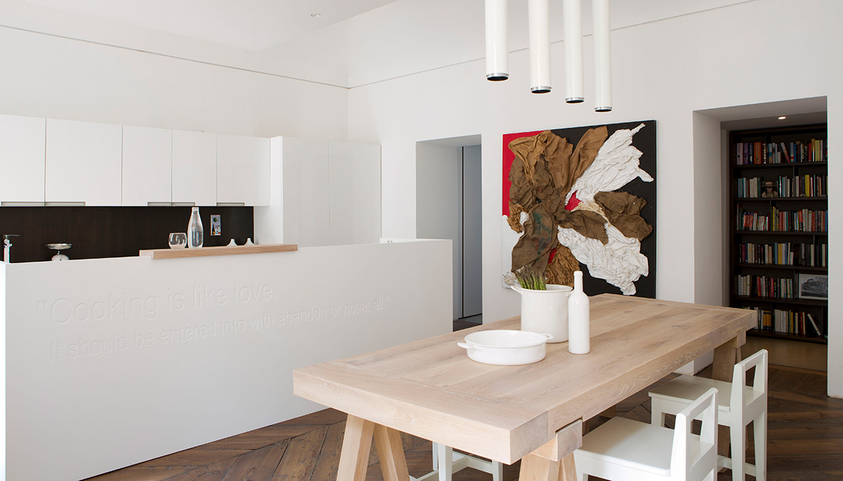 Cucina con grande tavolo in legno naturale e arredi bianchi