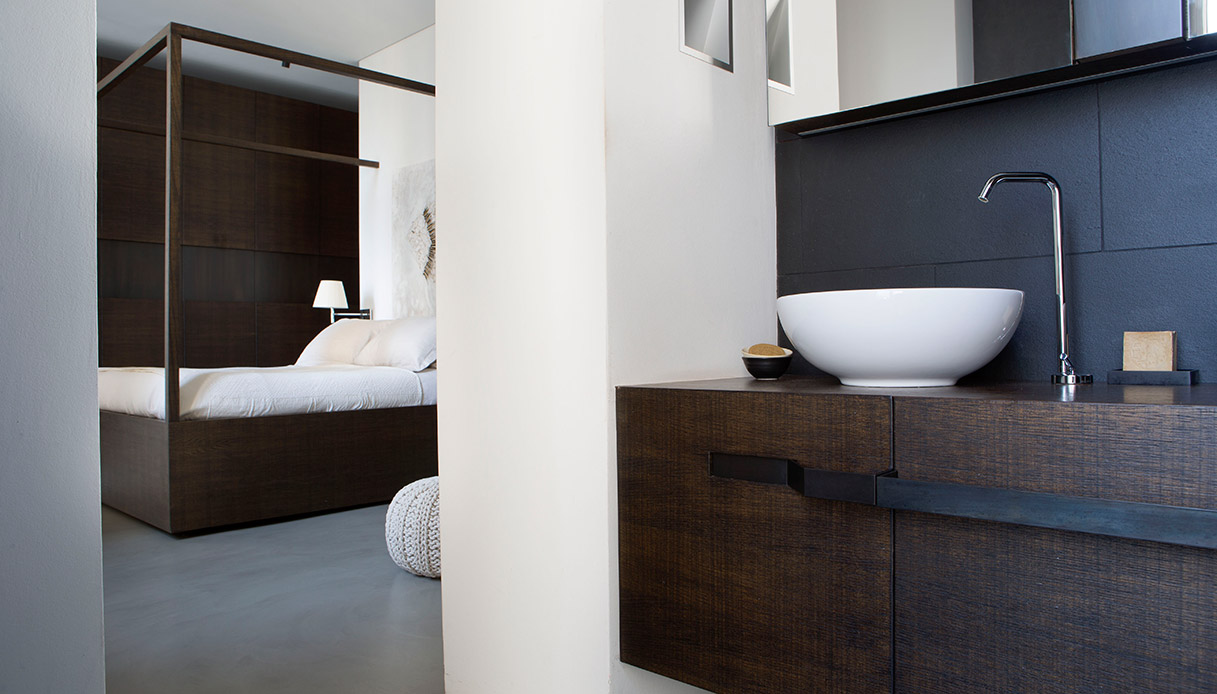 Bagno padronale con lavabo freestanding, legno scuro e marmo chiaro