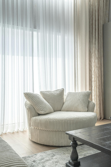 Poltrona arrotondata in tessuto morbido vicino a una finestra