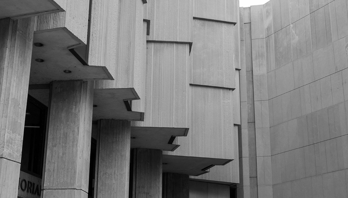 Dettaglio architettonico brutalista con cemento grezzo e volumi sporgenti