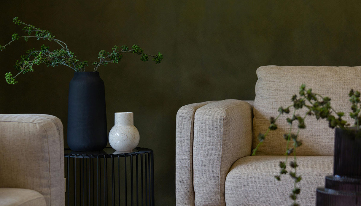 Soggiorno con parete verde petrolio e arredi in tessuti naturali secondo le tendenze design 2026