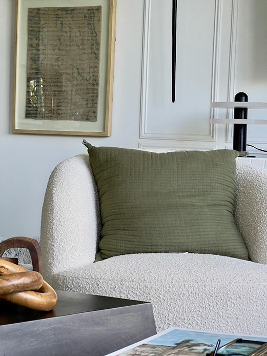 Poltrona in boucl&eacute; con cuscino verde in un interno ispirato al design 2026