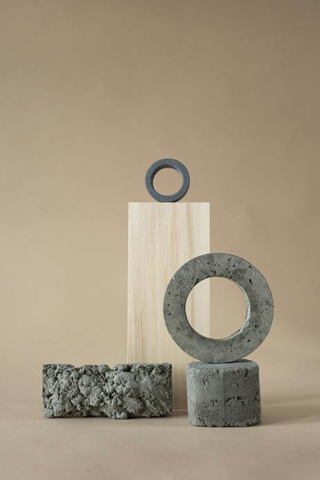 Oggetti decorativi geometrici in cemento e legno disposti come composizione scultorea.