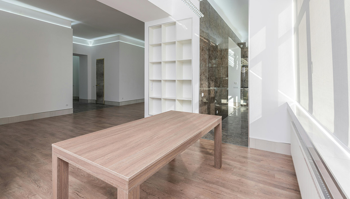 Tavolo in legno massello in uno spazio contemporaneo con superfici essenziali.