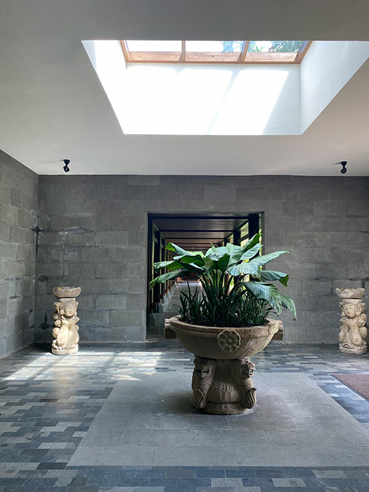 Corte interna con pavimentazione in pietra e elemento scultoreo centrale.