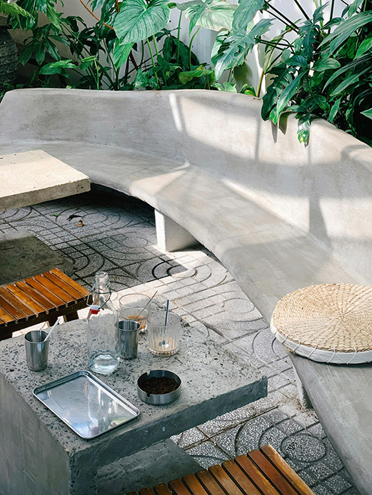 Spazio outdoor con sedute curve bianche in muratura e tavolini scultorei