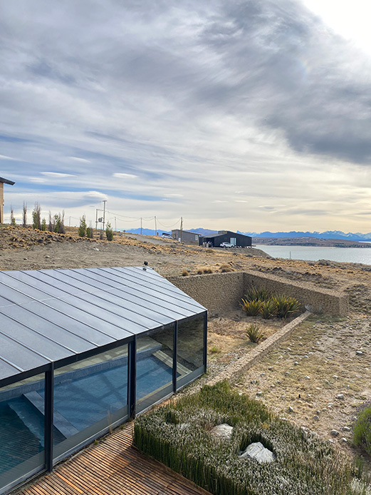 Struttura contemporanea con pareti in vetro e tetto basso inserita nel paesaggio costiero della Patagonia