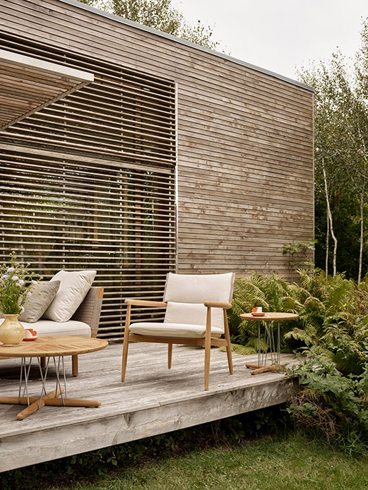 Arredi outdoor in teak non trattato su terrazza immersa nel verde, esempio di comfort progettuale.