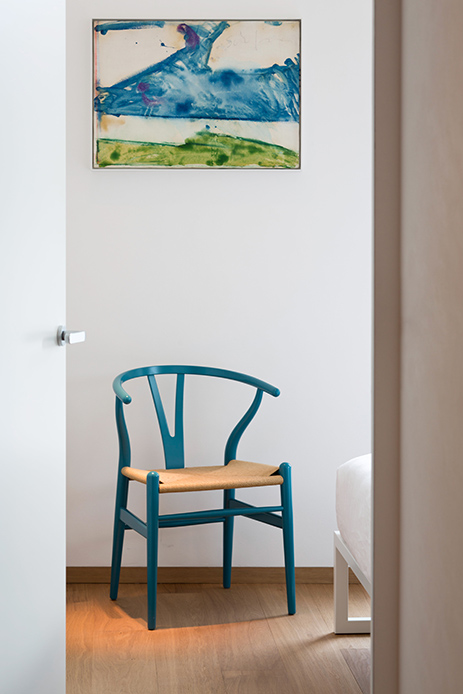 Ingresso dell’attico a Milano con sedia Wishbone blu petrolio, parquet in rovere naturale e quadro astratto alle pareti