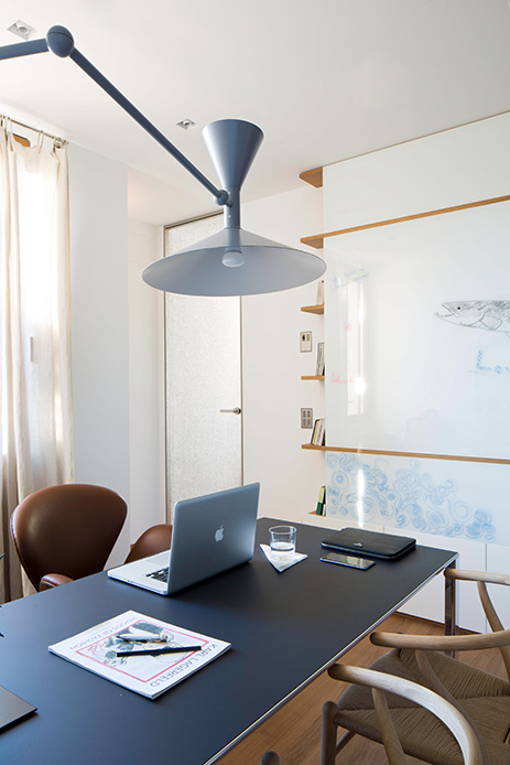 Studio dell’attico con scrivania nera, sedia in pelle, libreria retroilluminata e parete utilizzata come lavagna