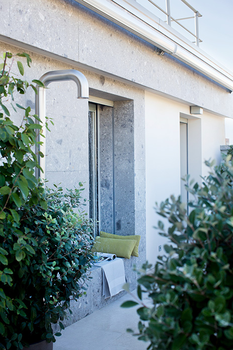 Terrazza dell’attico con piante e arbusti, rivestimento in pietra e dettagli architettonici moderni
