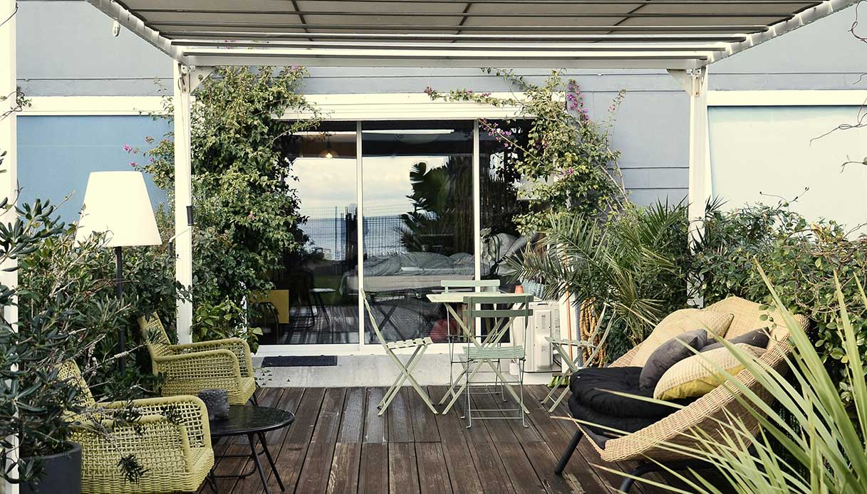 Balcone urbano arredato con piante e sedute outdoor, esempio di spazio esterno flessibile.