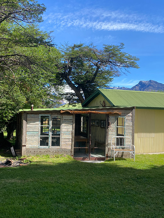Piccola costruzione rustica in legno riciclato con tetto semplice e giardino verde sullo sfondo montano