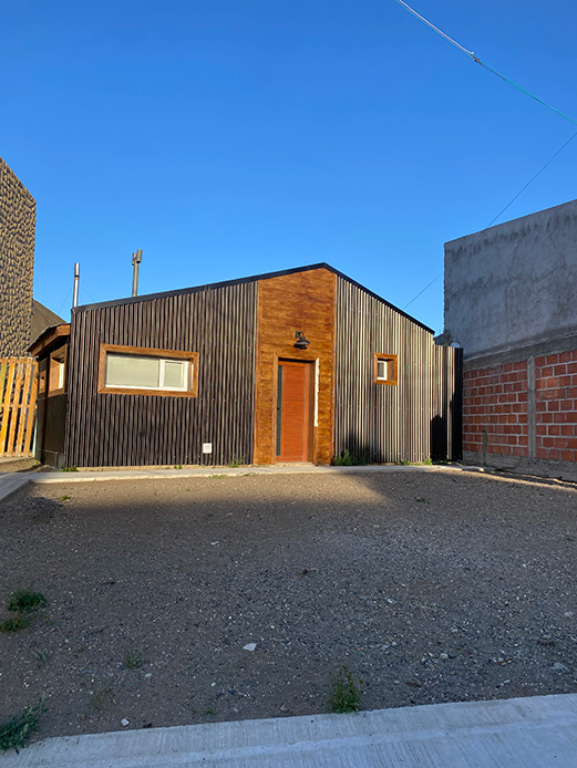 Casa moderna in Patagonia con facciata in chapa scura e ingresso rivestito in legno naturale