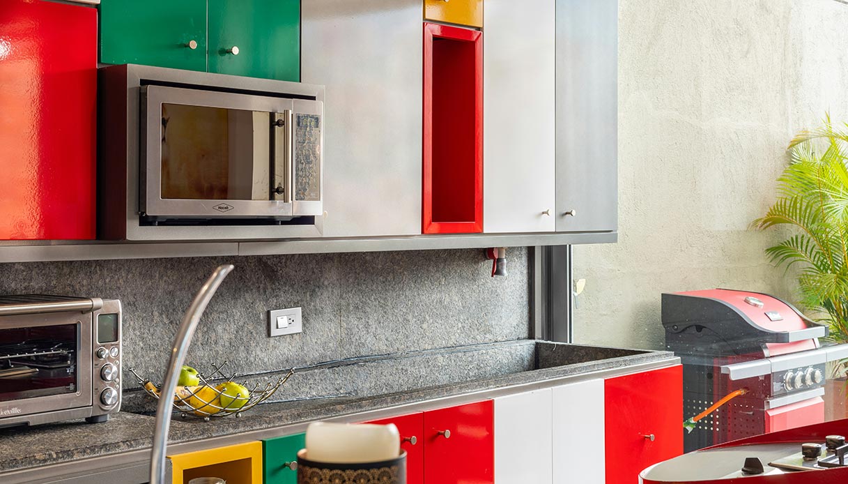 Cucina con ante rosse e verdi smaltate e piano in granito grigio