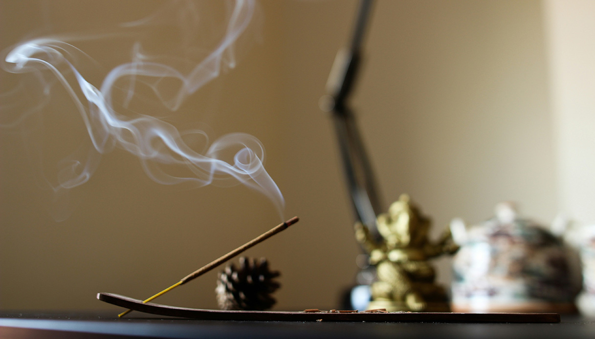 Bastoncino di incenso acceso su superficie minimale, simbolo di olfactive design.