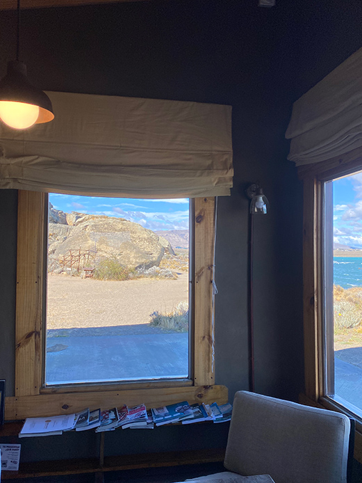 Interno con ampie finestre affacciate su lago e montagne, cornici in legno e luce naturale intensa