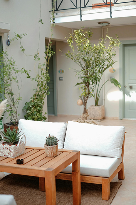 Divano e tavolino in legno naturale in un patio interno con piante in vaso
