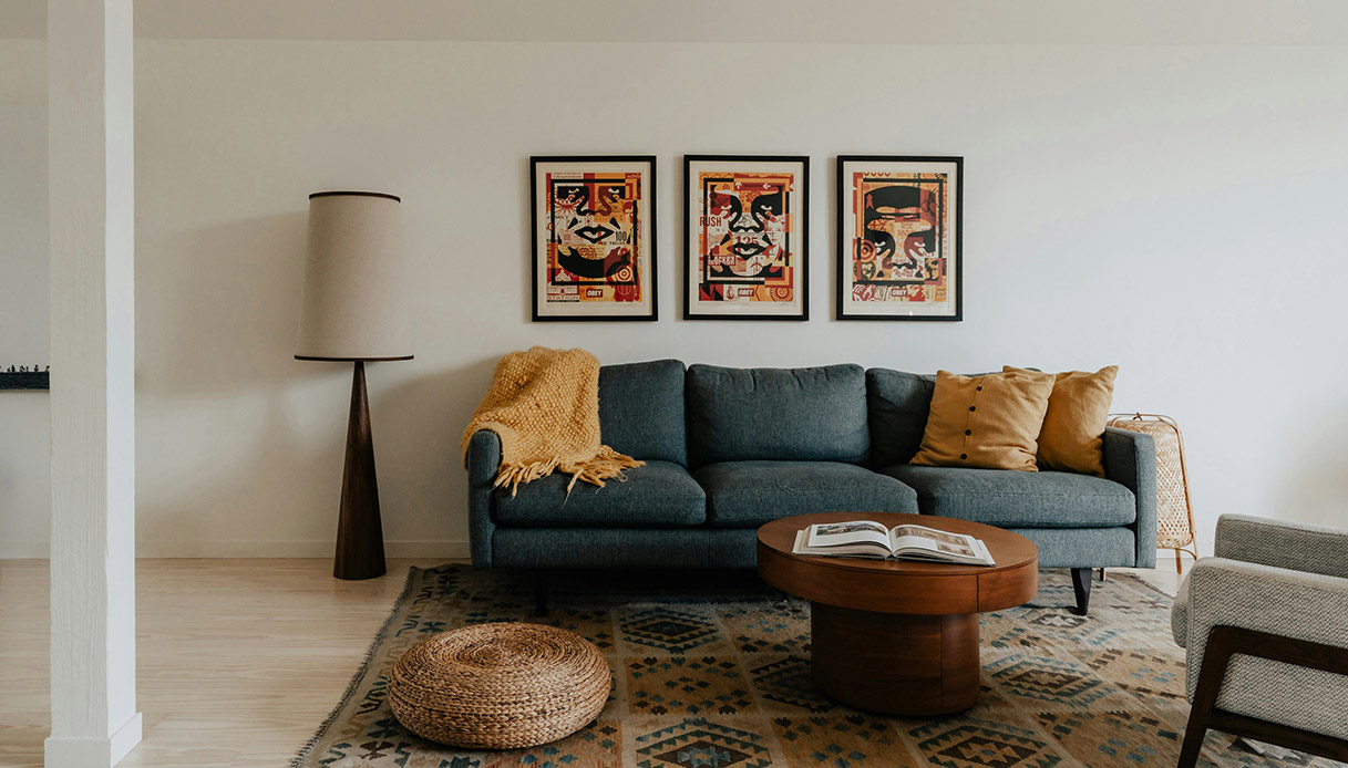 Pouf rotondo in fibra intrecciata davanti a un divano moderno in un salotto luminoso e arredato in stile casual.