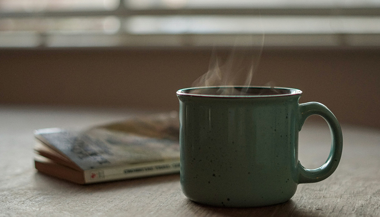 Tazza di bevanda calda su tavolo in legno, simbolo di comfort domestico in inverno.