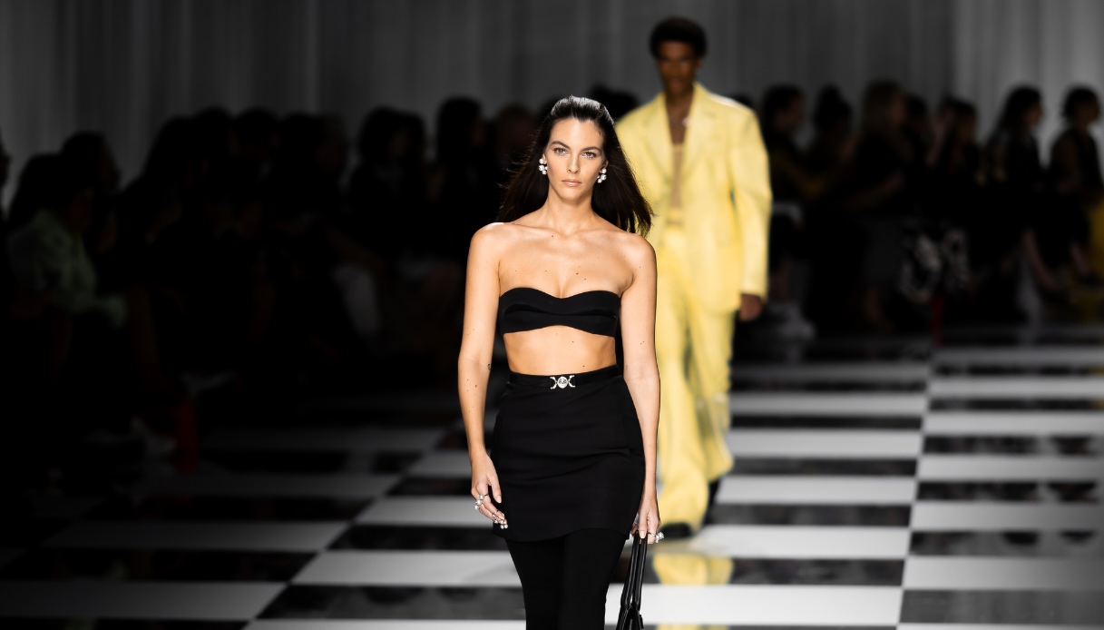 Vittoria Ceretti in passerella alla Milano Fashion Week con abito nero cut-out e pantaloni aderenti