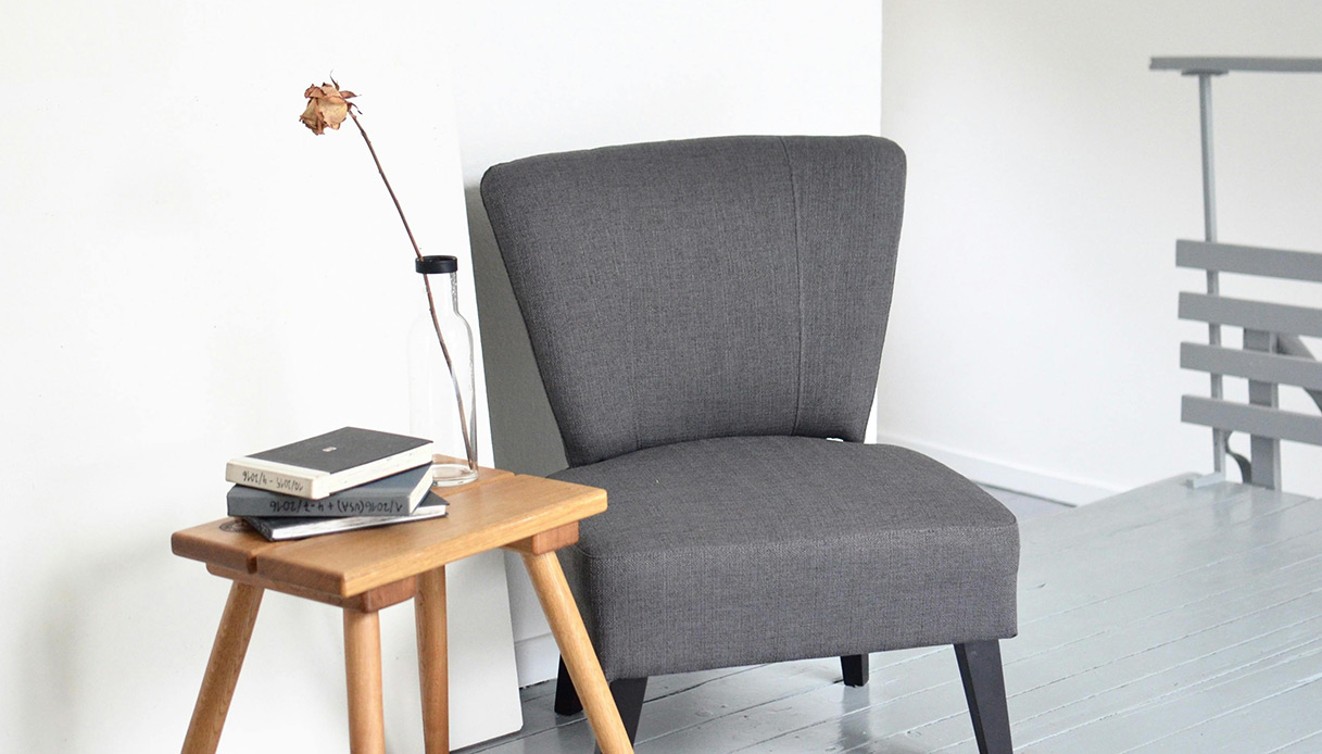 Angolo lettura minimal con poltrona grigia e tavolino in legno