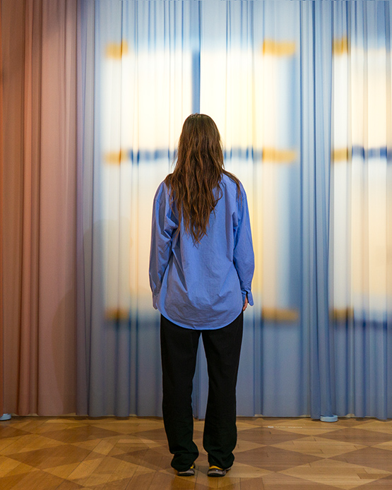 Yvonne Mak di spalle davanti a una tenda con finestre luminose stampate della serie Imprint