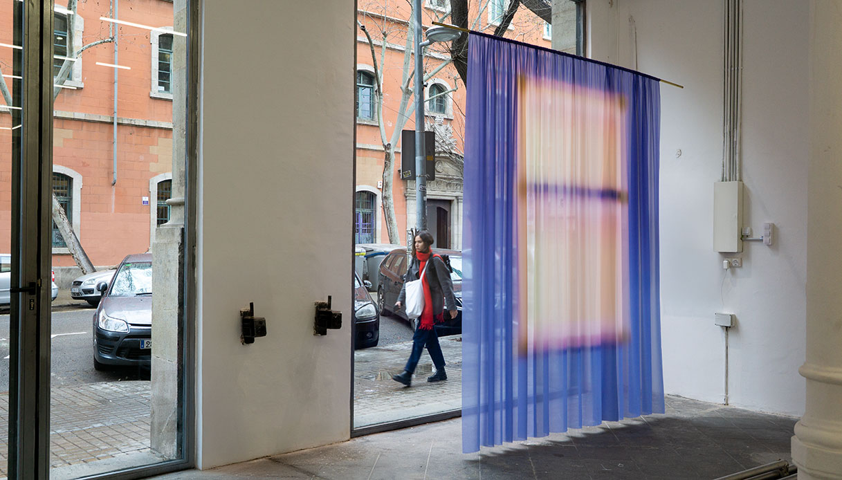 Installazione con tenda trasparente blu della serie Imprint di Yvonne Mak in uno spazio espositivo con vista sulla strada