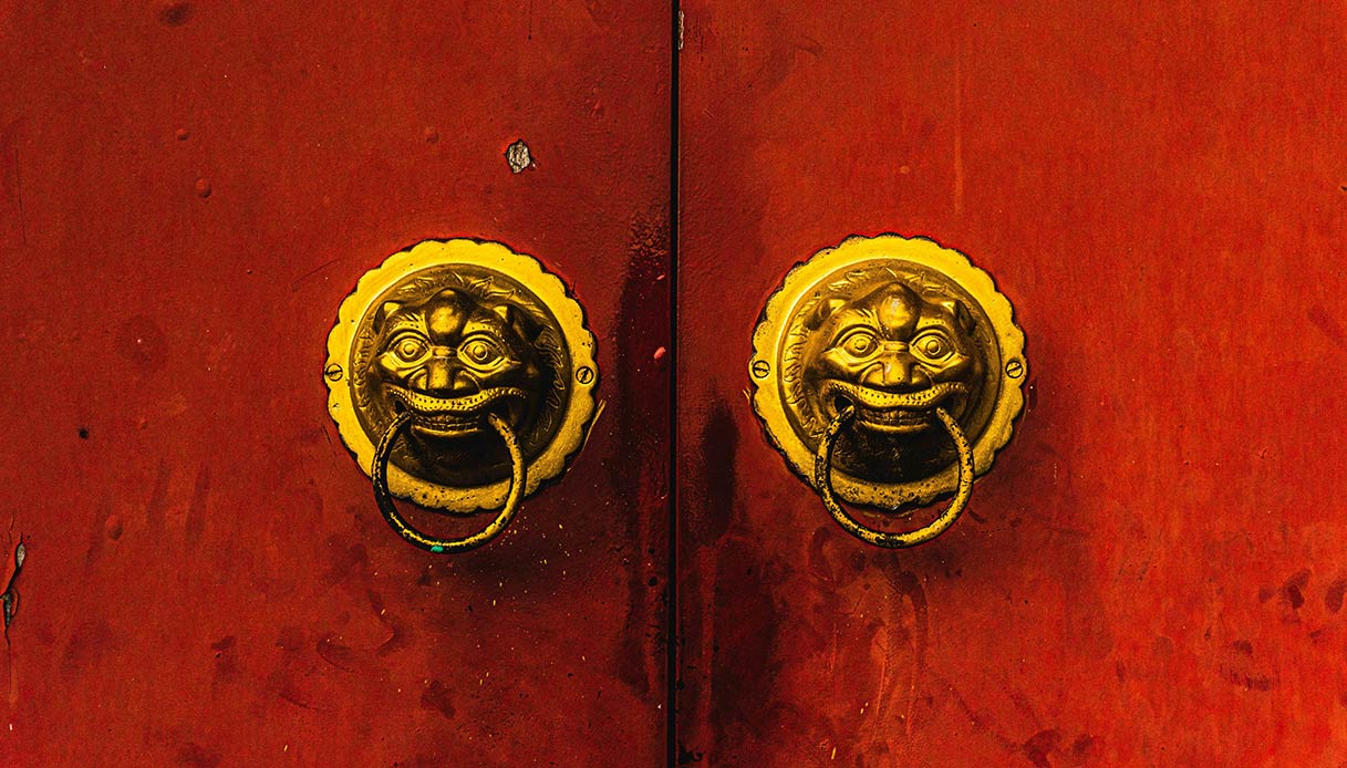 Battenti in ottone su porta rossa dal forte carattere decorativo